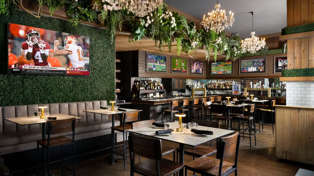 A crowded bar with a game on the TVs
