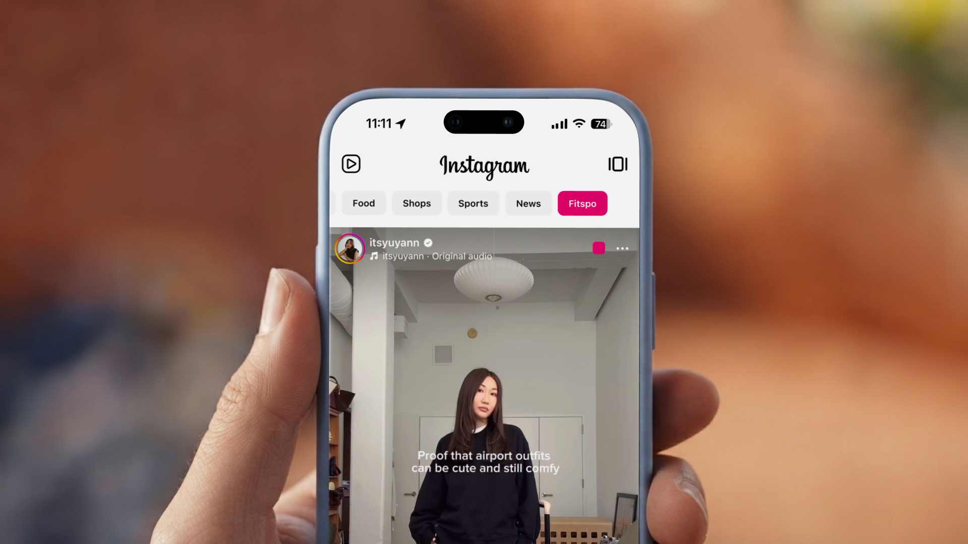 A hand holding a phone showing Instagram with list pills along the top