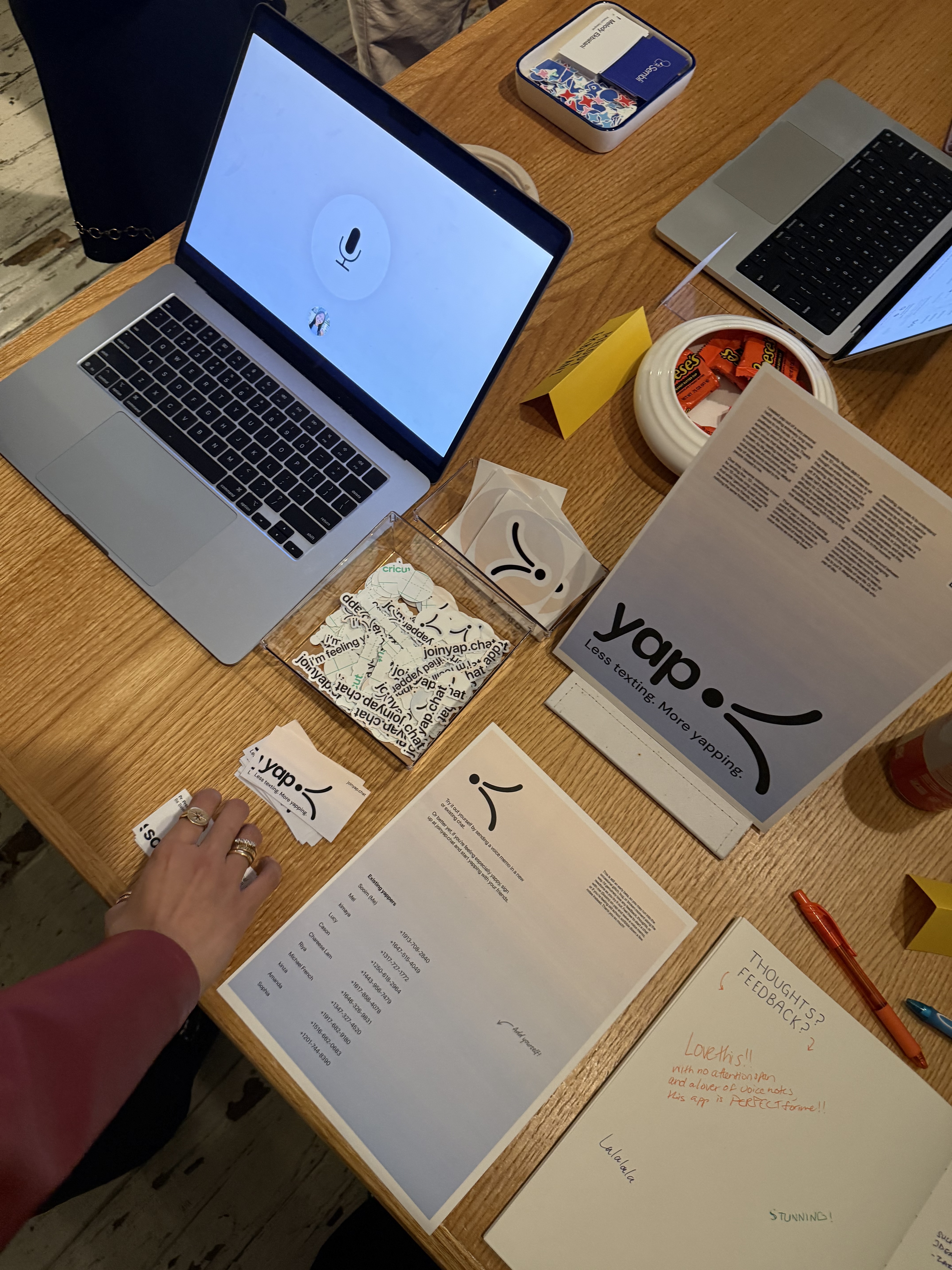 The yap station: yap running on a laptop, stickers, cards, the poster, and a feedback notebook